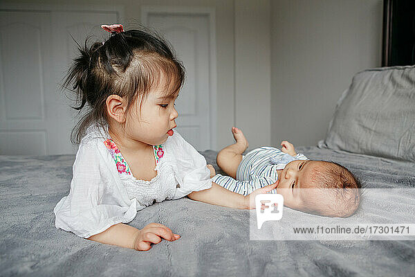 Cute Asian Chinese girl touching little newborn baby brother