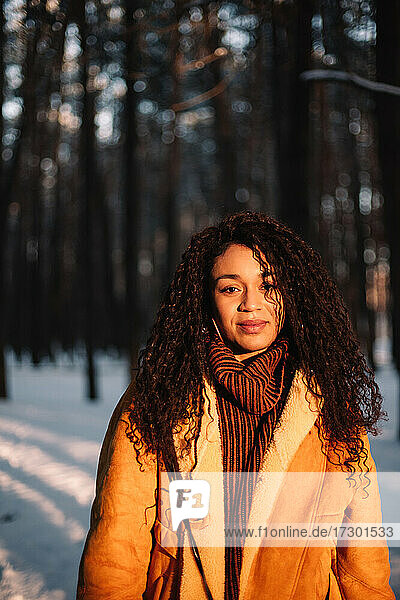 Portrait of young woman standing in park in winter during sunny day
