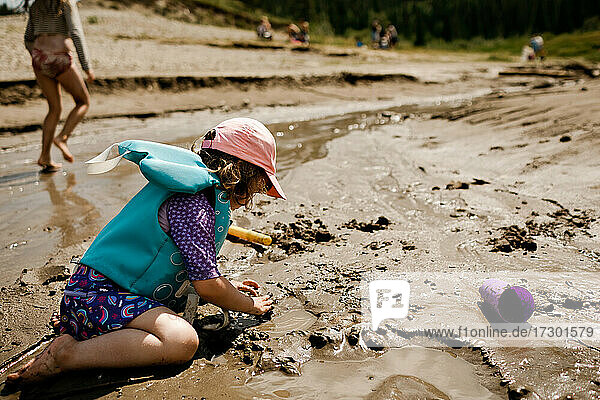 Young girl playing at the beach making a sand castle in the summer