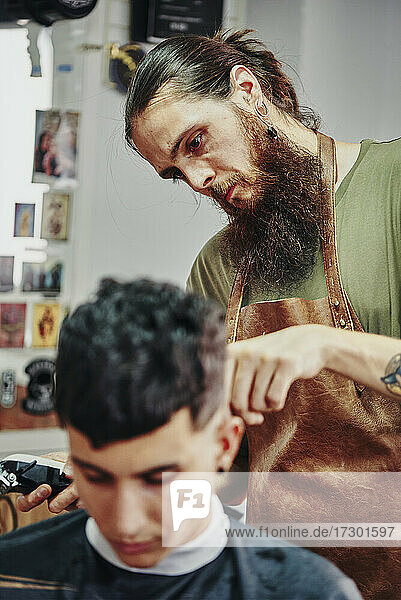 Ein Barbier rasiert einem Jungen die Haare ab