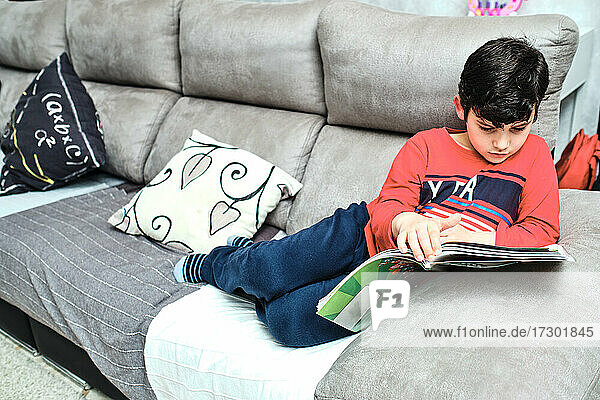 Kind lernt auf dem Sofa zu Hause