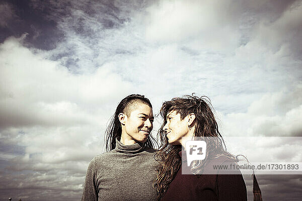 proud queer lesbian couple stand on rooftop with sky above in berlin