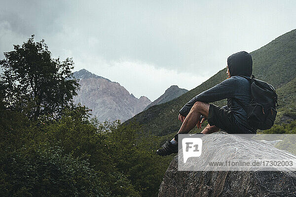 man sitting on rock in mountains