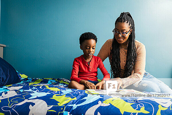 Mutter hilft ihrem Sohn beim Lernen im Schlafzimmer zu Hause