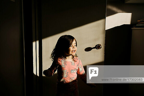 Junges Mädchen wirbelt vor der Schlafzimmertür im Sonnenlicht