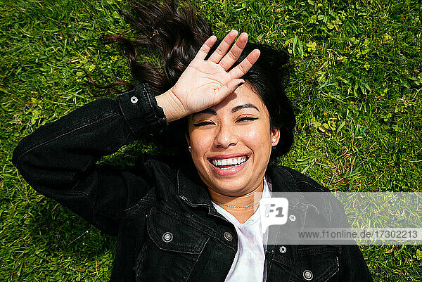 Overhead einer jungen lateinischen Frau  die auf dem Gras liegt und Spaß hat