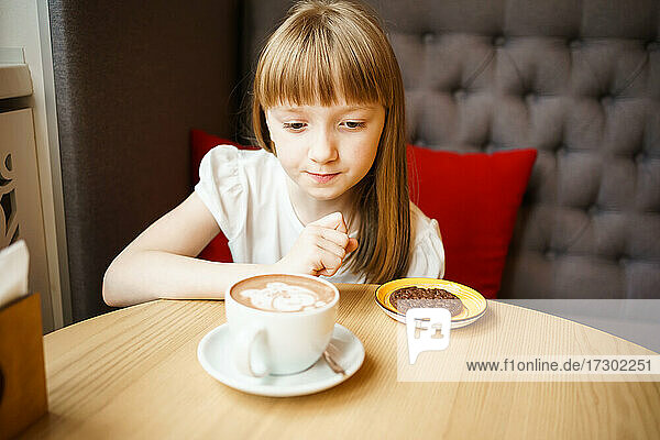 cute little girl looks at cocoa with a pattern