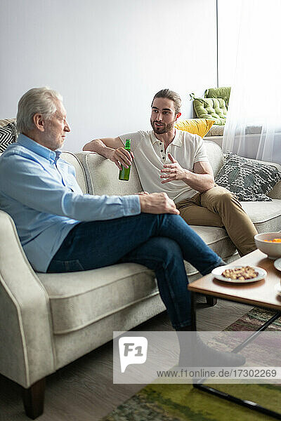 Ältere und junge Männer unterhalten sich auf einem Sofa