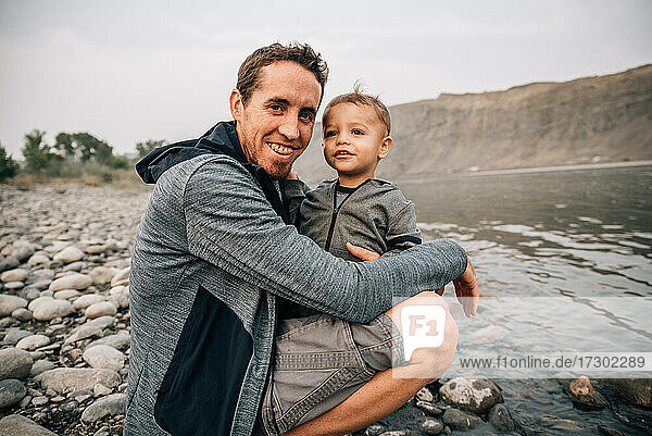 Dad and toddler hugging by yellowstone river on a nature walk