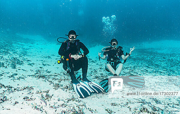 two friends relaxing on ocean floor in Raja Ampat