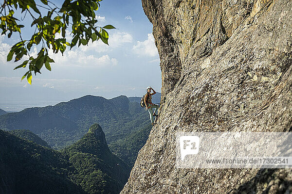 Beautiful view to female climber on steep rocky rainforest mountain