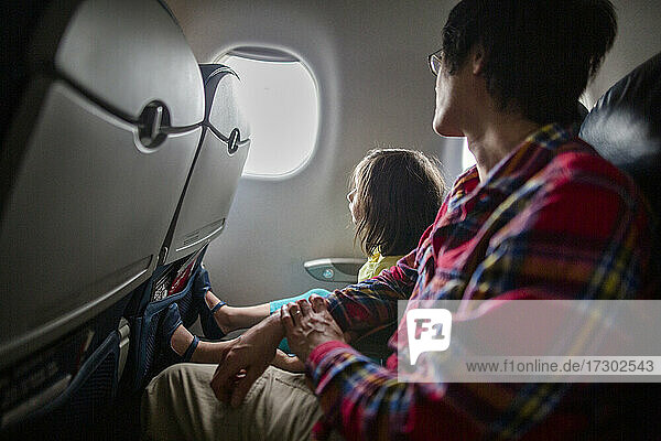 Ein kleines Mädchen und sein Vater sitzen zusammen im Flugzeug und schauen aus dem Fenster