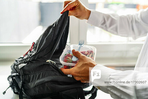 Junger Mann bewahrt seine Tupperware für gesunde Ernährung in seinem Rucksack auf