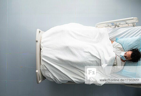 Junger Mann liegt schlafend auf einem Krankenhausbett. Overhead-Foto.