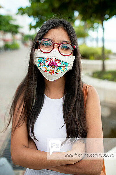 Hübsche junge Frau mit Gesichtsmaske und Brille lächelt