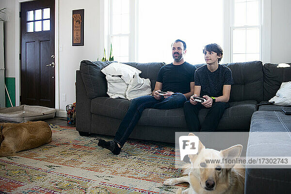 Vater und Sohn spielen zusammen Videospiele auf der Couch.