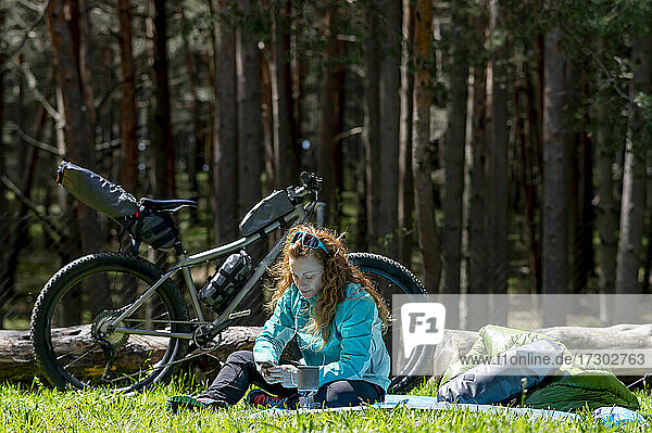 Eine Frau benutzt ein Mobiltelefon neben ihrem Adventure-Bike