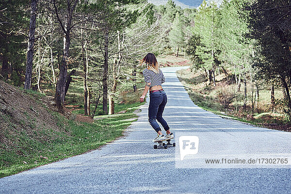 Eine Frau mit einem Skateboard auf einer Bergstraße