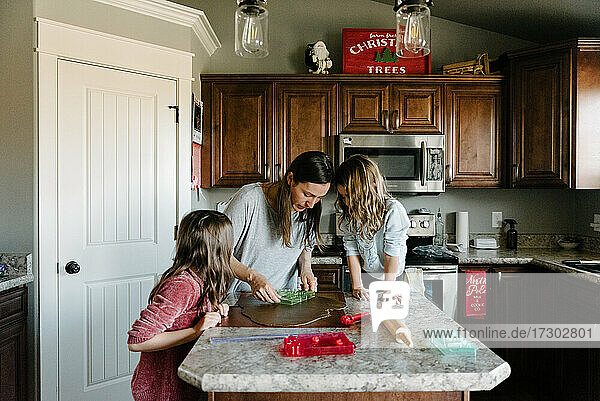 Mutter macht Lebkuchenhäuser mit ihren Töchtern zu Hause