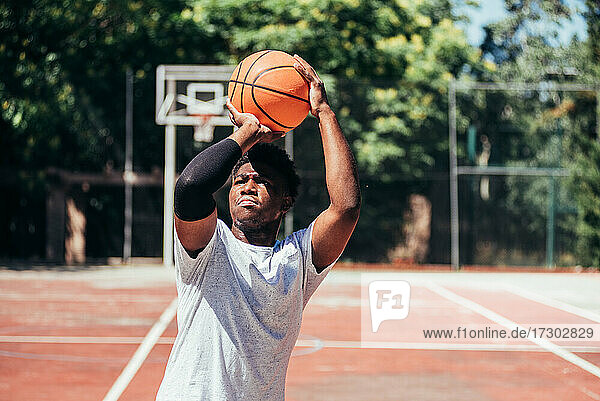 Porträt eines afroamerikanischen schwarzen Jungen  der auf einem städtischen Platz Basketball spielt.