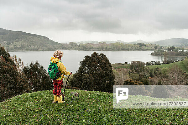 Kind mit Rucksack mit Blick auf einen See in Neuseeland