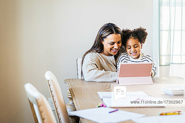 Happy woman and daughter using digital tablet at home