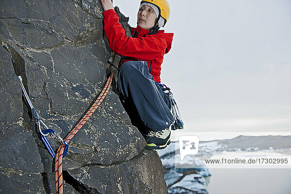 female climber scaling step rock face in Skaftafell / Iceland