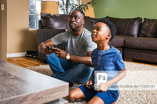 Vater und Sohn spielen ein Videospiel im heimischen Wohnzimmer