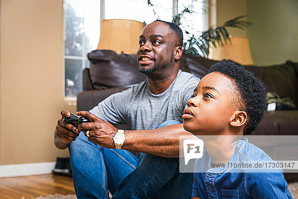Father and son playing video game in living room at home