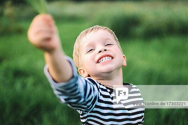 Kleiner Junge lächelnd in einem großen Feld auf dem Lande
