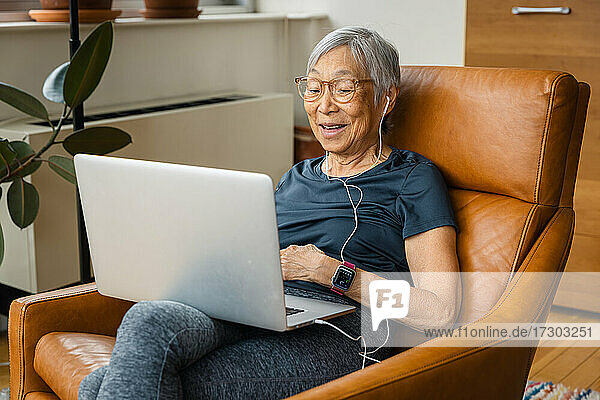 Porträt einer lächelnden älteren Frau  die zu Hause einen Laptop benutzt