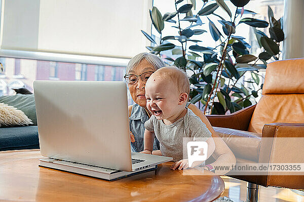 Ältere Frau sitzt mit ihrer Enkelin und führt einen Videogespräch auf dem Laptop