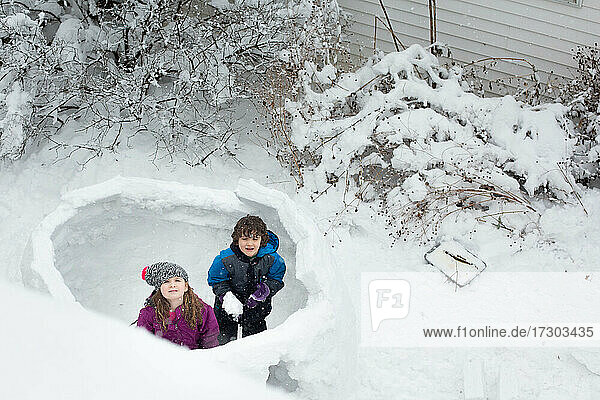Zwei Kinder bauen im Winter eine Schneefestung