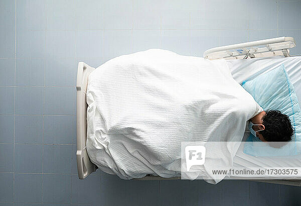 Junger Mann liegt schlafend auf einem Krankenhausbett. Overhead-Foto.