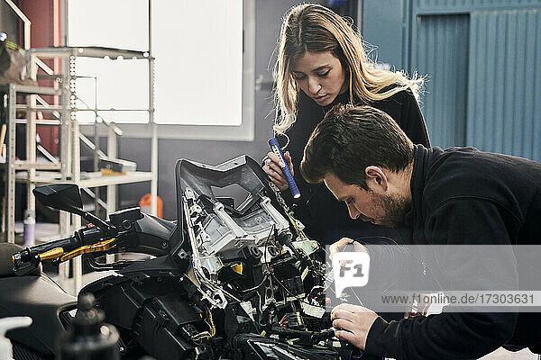 Eine Frau und ein Mann arbeiten zusammen in einer Autowerkstatt