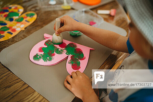 Close up of child hands painting colorful butterfly with sponge stamps