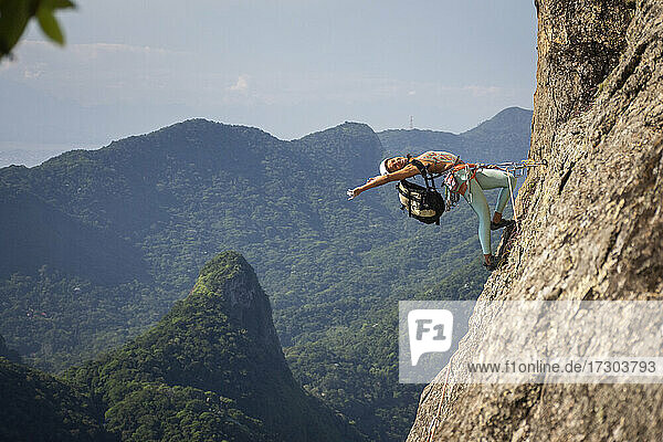 Beautiful view to female acrobat climber bending body back on mountain