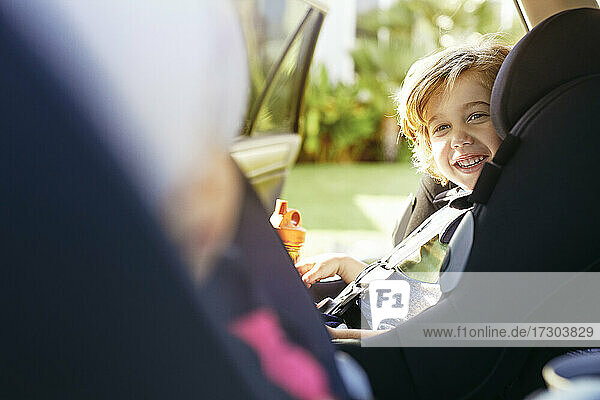 Niedlicher Junge lächelnd im Auto sitzend