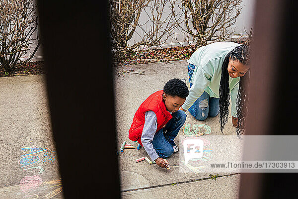 Mutter und Sohn haben Spaß daran  gemeinsam Kreide auf Beton im Hinterhof zu benutzen