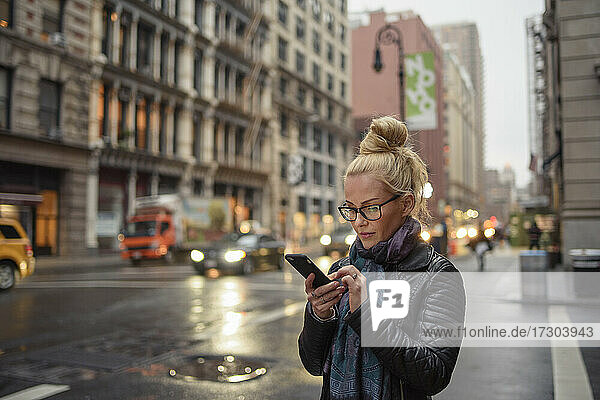 Attraktive Frau benutzt ihr Smartphone auf einer belebten städtischen Straße