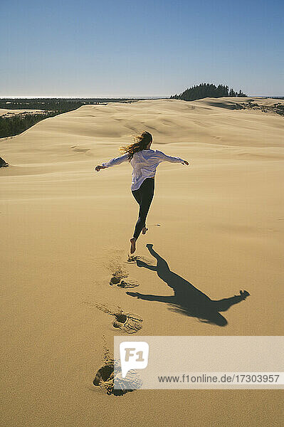 Weiblich Springen in der Luft in den Sanddünen