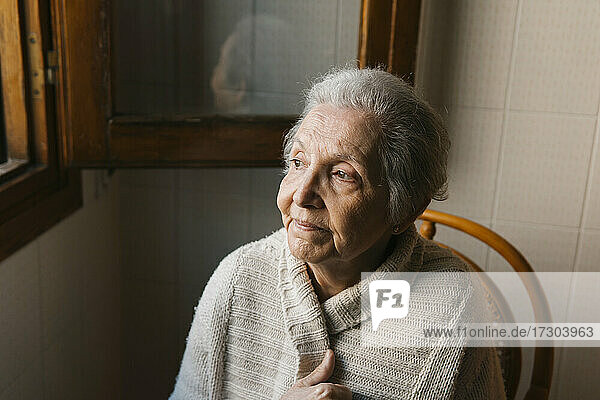 Porträt einer älteren Frau  die aus dem Fenster schaut