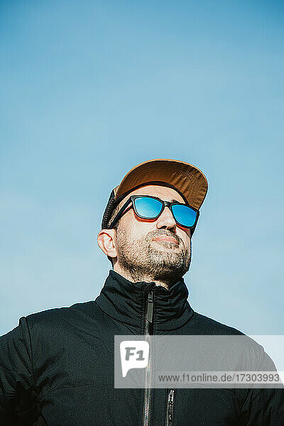 Mann mit Sonnenbrille und Mütze an einem sonnigen Tag