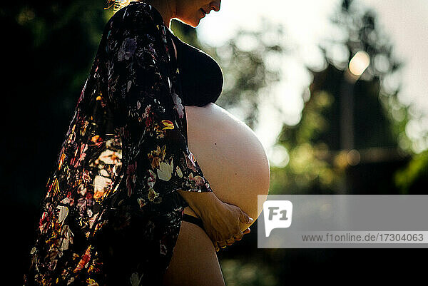 Seitenansicht der schwangeren Frau mit großem Bauch draußen in der Natur
