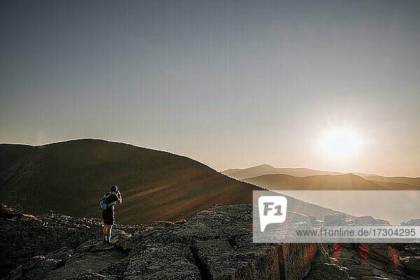 Male hiker takes photo of sunrise over White Mountains New Hampshire
