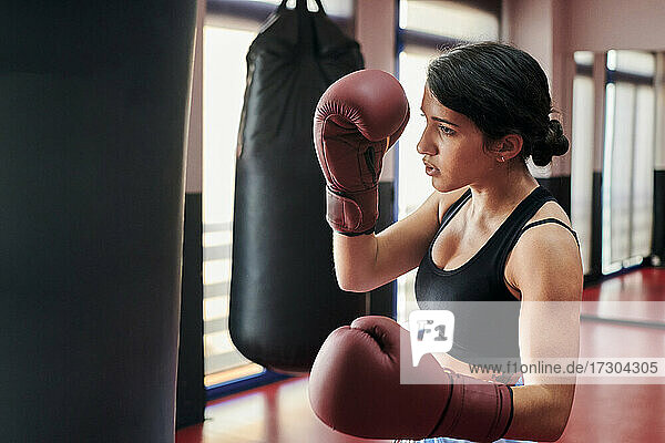Woman trains with a punching bag in a Muay Thai gym