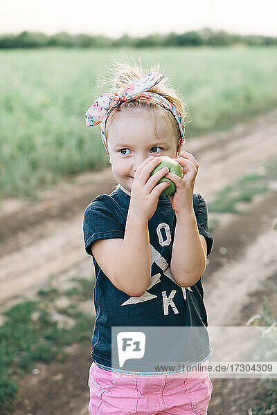 cute girl holds a green apple in her hands