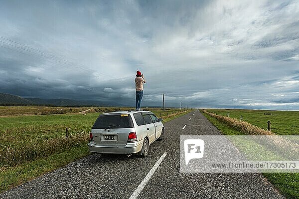 Guy with camera on car roof  Karamea  Buller District  West Coast  South Island  New Zealand  Oceania