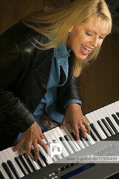 Musikerin singt  während sie Digitalpiano spielt