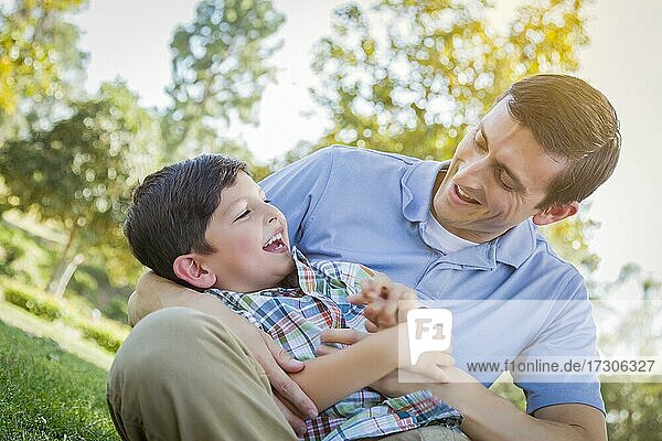 Loving young father tickling son in the park
